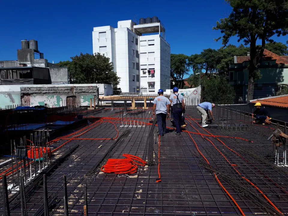 Equipo de Proelectric tendiendo canalizaciones naranjas sobre la losa del Edificio U3031